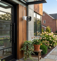 EvokLiving smart outdoor camera with AI face detection, showing a sleek black camera mounted outdoors with detection icons on the image.